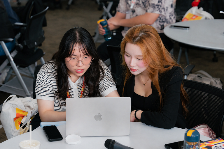 Two learners collaborating and looking at a laptop in a workshop